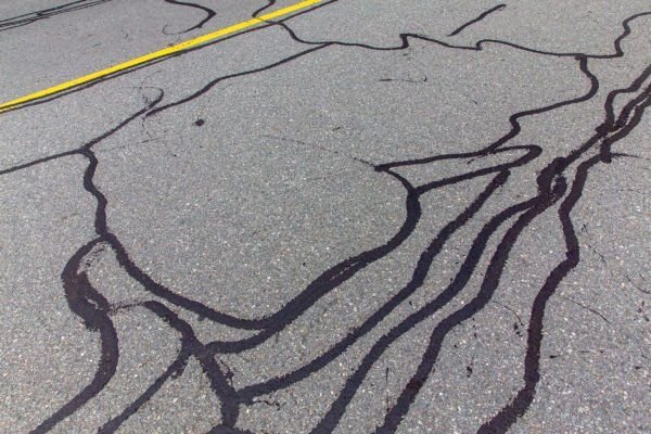 An adhesive sealant is injected into cracks in the pavement to prevent moisture and non-compressible materials from infiltrating the pavement.