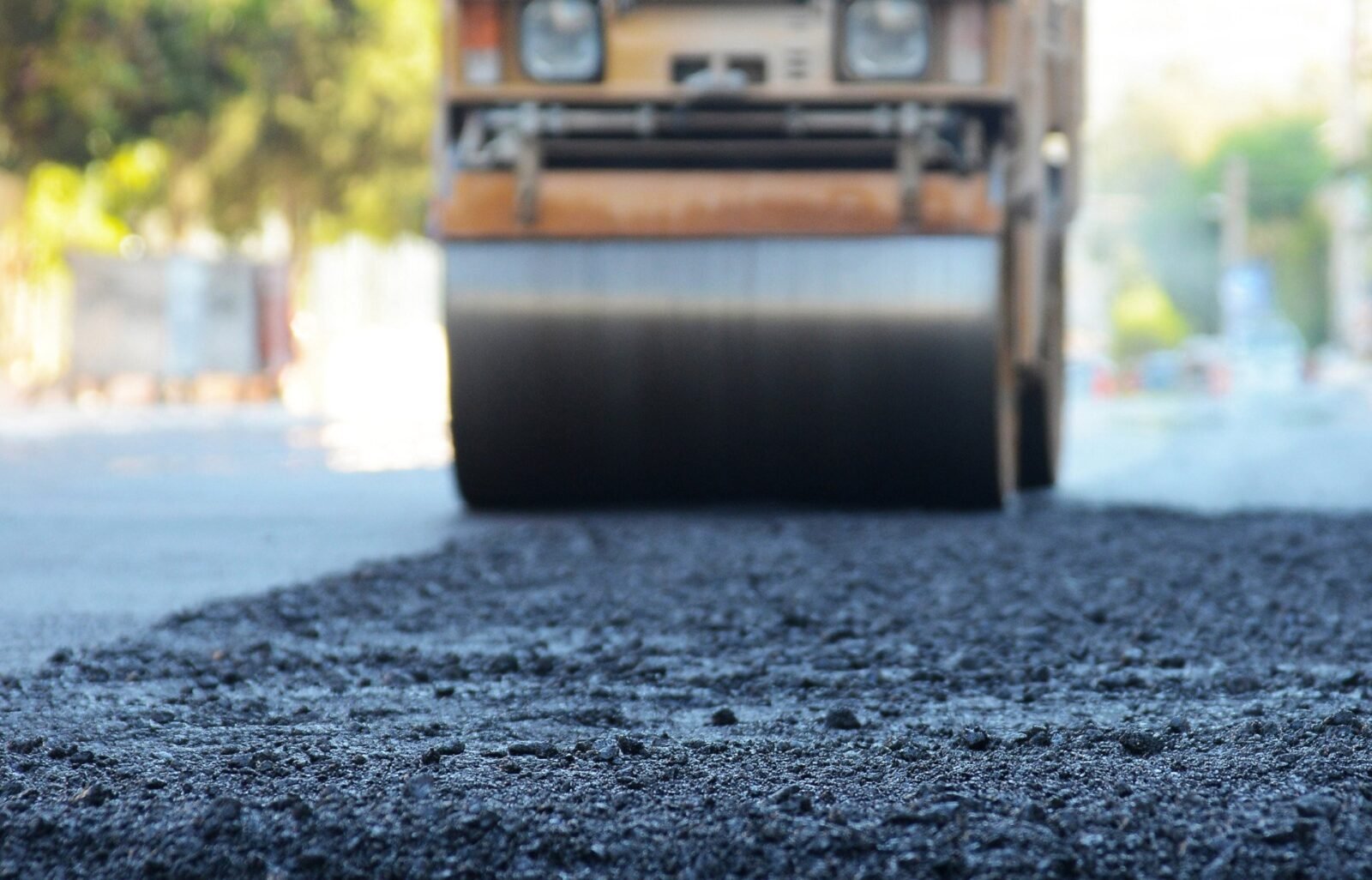 A road roller leveling out the new asphalt surface.